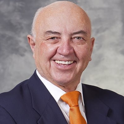 photo of Dr. Hans Sollinger from the shoulders up, in a dark suit, white shirt and orange tie