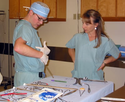 Surgeon points to chest to demonstrate procedure while student looks on