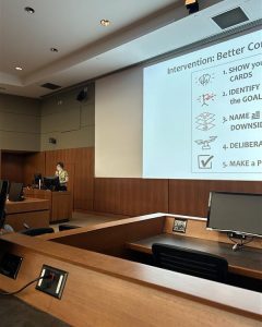 Dr. Kate Telma stands at a podium at the front of the auditorium