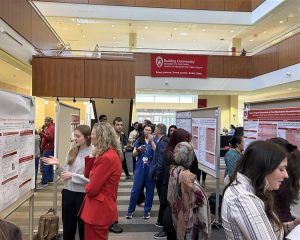 People stand at posters discussing research happening in the department