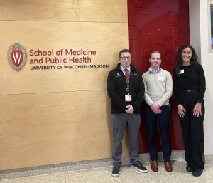Dr. Patrick Carney stands next to the two other flash talk awardees in front of a sign that says "School of Medicine and Public Health University of Wisconsin-Madison"