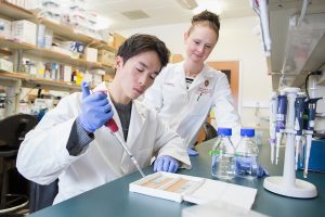 Dr. Evie Carchman in a lab coat working in the lab with a trainee