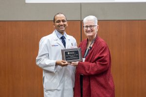 Dr. Nabeel Zafar stands in a white coat accepting his award