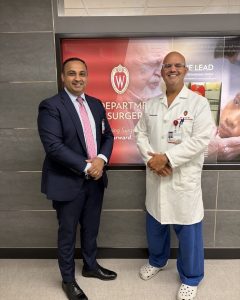 Drs. Sameer Hirji and John Stulak stand together for a picture in front of a UW Crest