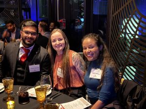 Kaleem Ahmed, Meaghan Clark, and Faith Dickerson sitting at a table, smiling for a picture