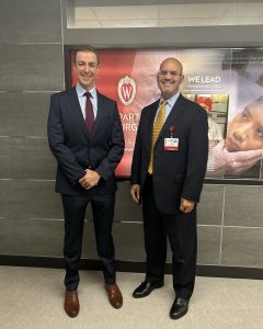 Dr. Daniel Harris and Dr. John Stulak standing together for a picture in front of the UW Crest