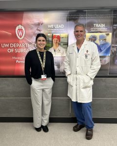 Drs. Caroline Cardenas and Ben Zarzaur stand together for a picture in front of the UW Crest
